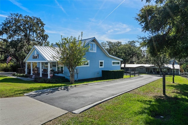 view of home's exterior with metal roof, a yard, a standing seam roof, and covered porch