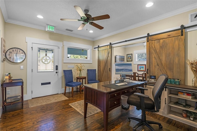 office space with a barn door, dark wood-style flooring, visible vents, a ceiling fan, and ornamental molding