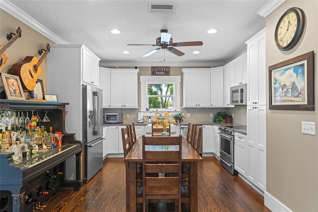 kitchen featuring premium appliances, visible vents, decorative backsplash, dark wood-style floors, and crown molding