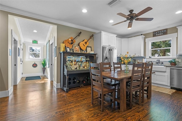 dining area with dark wood-style floors, baseboards, visible vents, and crown molding