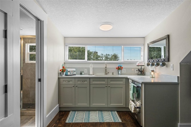 kitchen with a textured ceiling, light countertops, a sink, and dark wood finished floors