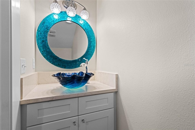 bathroom with a textured wall and vanity