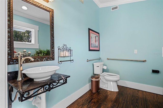 bathroom featuring baseboards, visible vents, ornamental molding, wood finished floors, and a sink