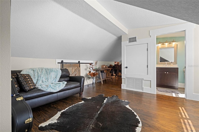 living room featuring visible vents, vaulted ceiling, a textured ceiling, and wood finished floors