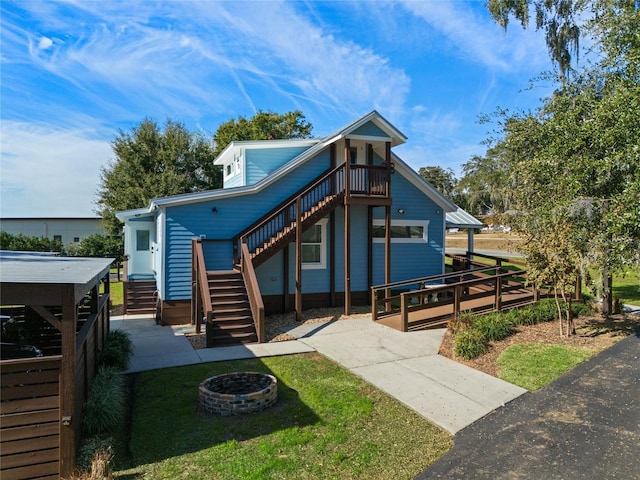 view of front of home featuring a fire pit, stairway, a front yard, and a wooden deck