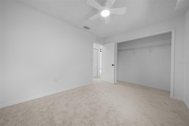 unfurnished bedroom featuring light carpet, ceiling fan, a closet, and a textured ceiling