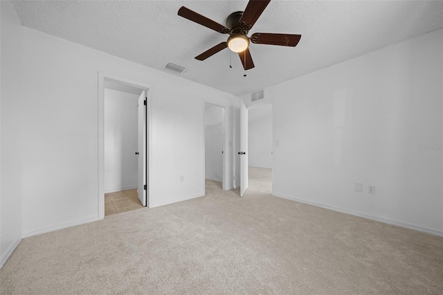 spare room featuring ceiling fan, light carpet, and a textured ceiling