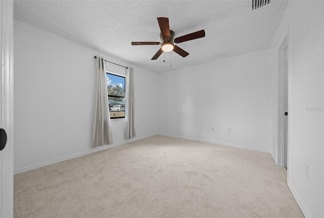 unfurnished room with ceiling fan, light colored carpet, and a textured ceiling