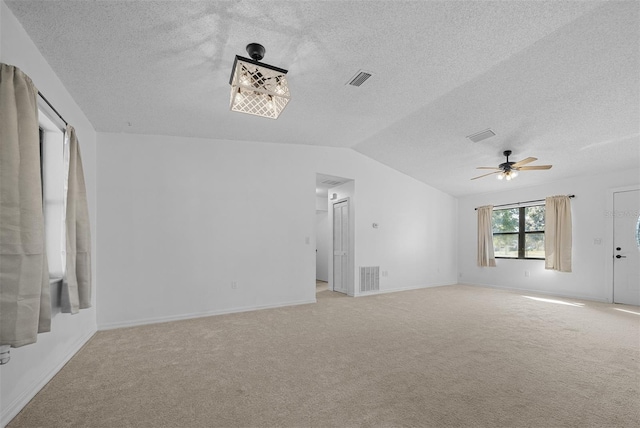 carpeted empty room with vaulted ceiling, ceiling fan, and a textured ceiling