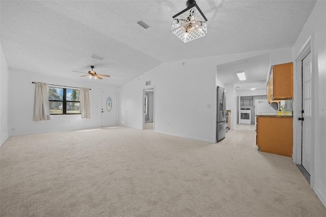 unfurnished living room featuring a textured ceiling, vaulted ceiling, light colored carpet, and ceiling fan