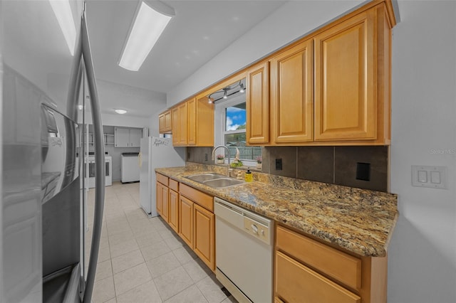 kitchen featuring sink, white appliances, washer and clothes dryer, backsplash, and light stone counters