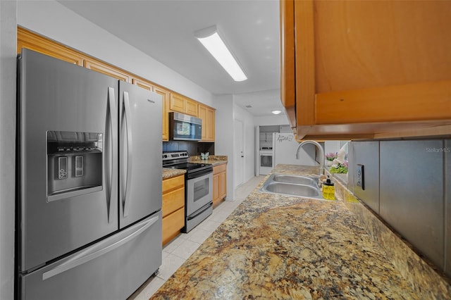 kitchen featuring sink, appliances with stainless steel finishes, stone countertops, light brown cabinetry, and light tile patterned flooring