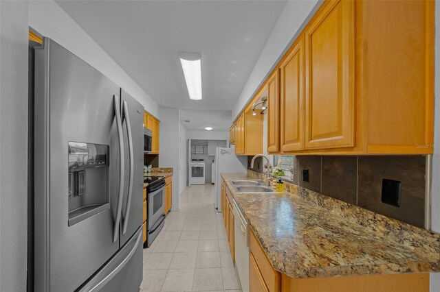 kitchen featuring stone counters, light tile patterned flooring, sink, backsplash, and stainless steel appliances