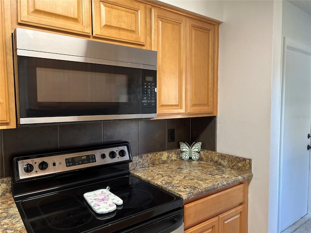 kitchen with appliances with stainless steel finishes and dark stone countertops