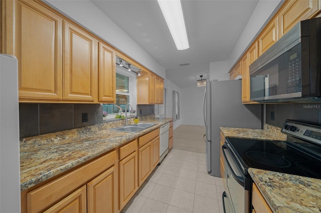 kitchen with light stone counters, appliances with stainless steel finishes, sink, and light tile patterned floors