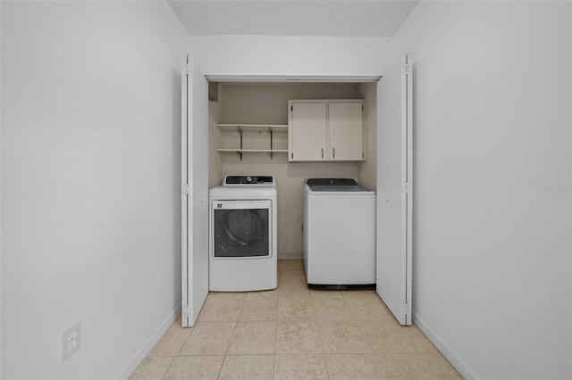 laundry room with cabinets, washing machine and clothes dryer, and light tile patterned flooring