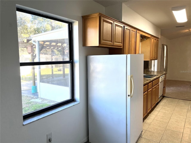 kitchen with dark stone countertops, light tile patterned floors, and white appliances