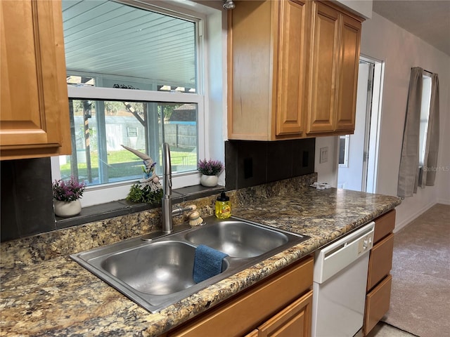 kitchen with dishwasher, dark stone countertops, sink, and light colored carpet