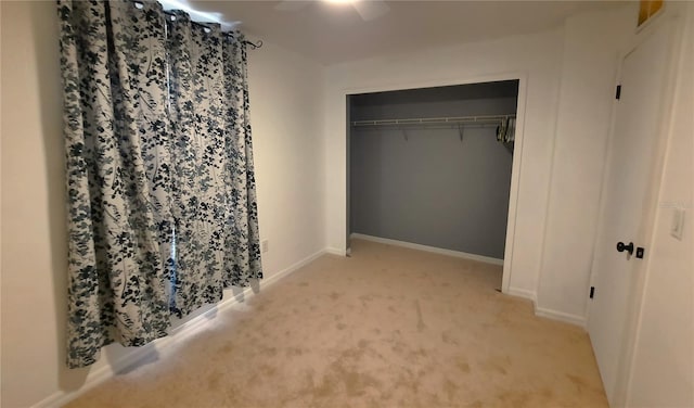 unfurnished bedroom featuring ceiling fan, light colored carpet, and a closet