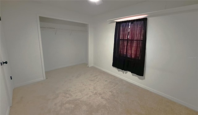 unfurnished bedroom featuring light colored carpet and a closet