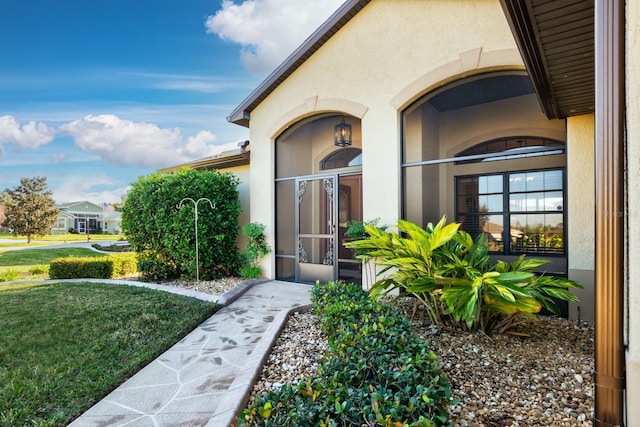 view of exterior entry featuring a lawn