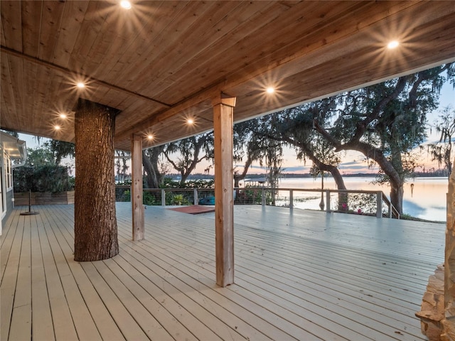 deck at dusk featuring a water view