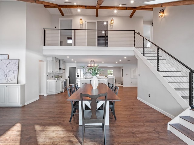 dining room featuring a towering ceiling, dark hardwood / wood-style floors, and beam ceiling