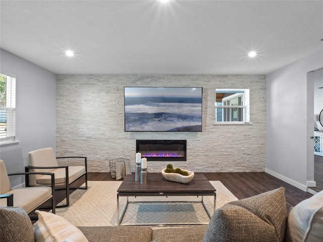 living room with wood-type flooring and a stone fireplace