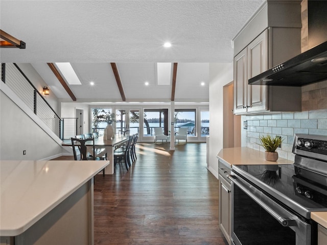 kitchen with wall chimney exhaust hood, stainless steel electric range, backsplash, lofted ceiling with beams, and gray cabinetry