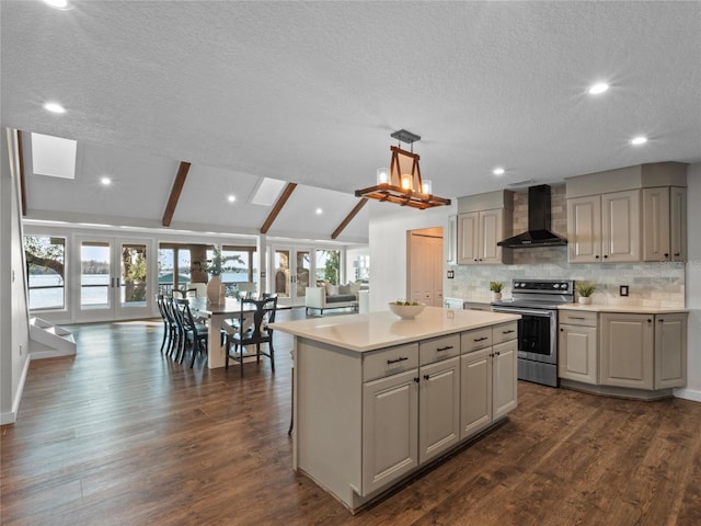 kitchen featuring hanging light fixtures, a center island, lofted ceiling with beams, stainless steel electric range oven, and wall chimney range hood