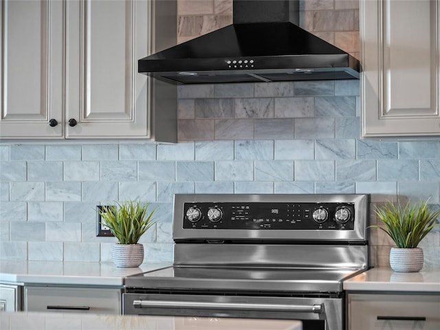 kitchen featuring white cabinets, wall chimney range hood, backsplash, and stainless steel range with electric stovetop