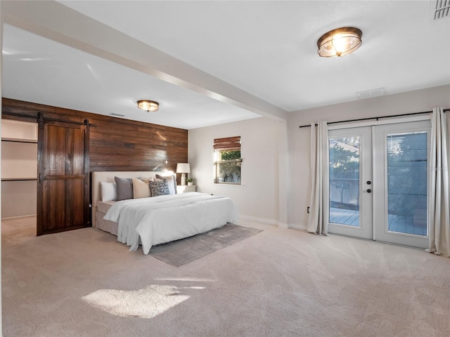 unfurnished bedroom featuring multiple windows, access to outside, wooden walls, and a barn door