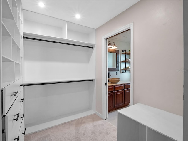 walk in closet featuring light colored carpet and sink