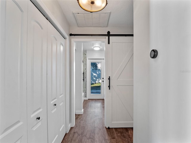 corridor featuring a textured ceiling, hardwood / wood-style floors, and a barn door