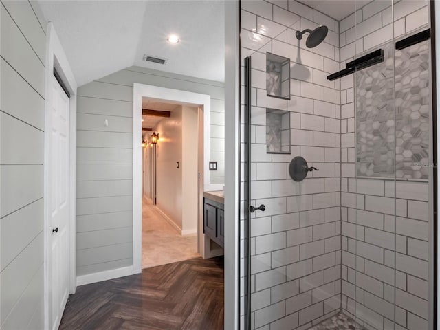 bathroom with vanity, parquet floors, vaulted ceiling, and tiled shower