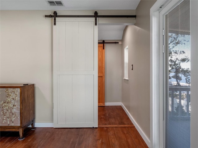 interior space with a barn door and dark hardwood / wood-style floors