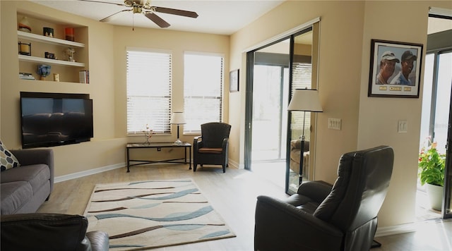 living room with ceiling fan, built in features, and light hardwood / wood-style floors