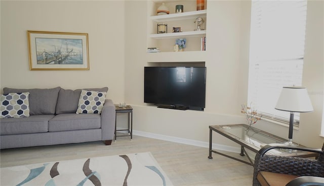 living room with built in shelves and light hardwood / wood-style flooring