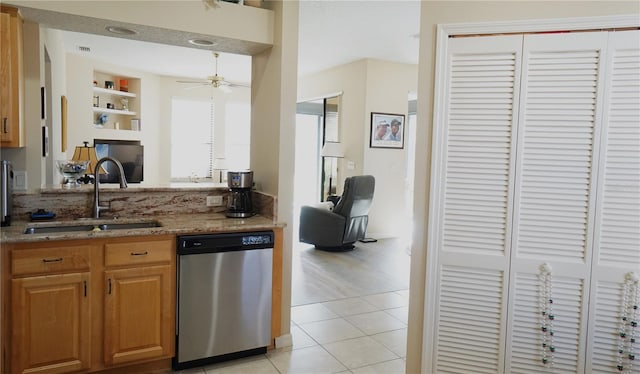 kitchen with dishwasher, sink, light stone counters, built in features, and light tile patterned flooring