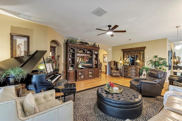 living room featuring ceiling fan, hardwood / wood-style floors, and a textured ceiling