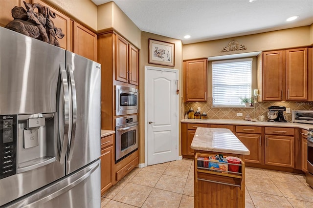 kitchen featuring decorative backsplash, appliances with stainless steel finishes, a center island, and light tile patterned floors