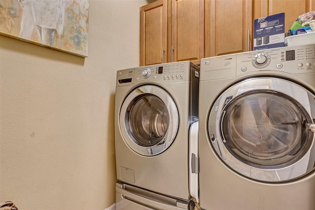 clothes washing area featuring cabinets and independent washer and dryer