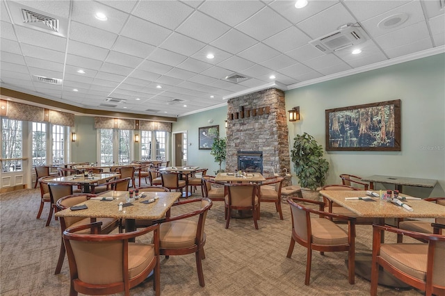 dining space with carpet, a drop ceiling, crown molding, and a fireplace