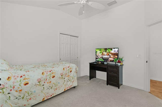 bedroom with ceiling fan, a closet, light carpet, and lofted ceiling