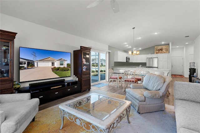 living room featuring lofted ceiling, ceiling fan with notable chandelier, and light hardwood / wood-style flooring