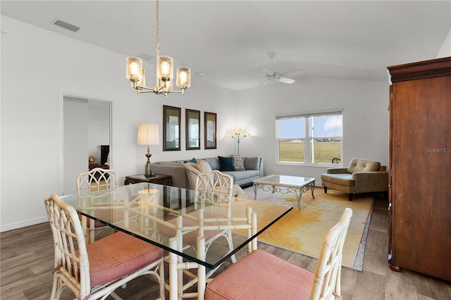 dining area with ceiling fan with notable chandelier and hardwood / wood-style floors