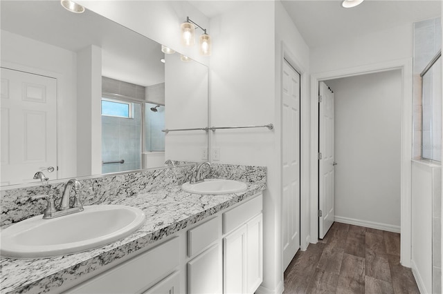 bathroom featuring a shower with shower door, hardwood / wood-style flooring, and vanity