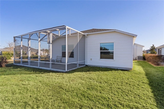 back of property featuring glass enclosure, a yard, and central AC unit