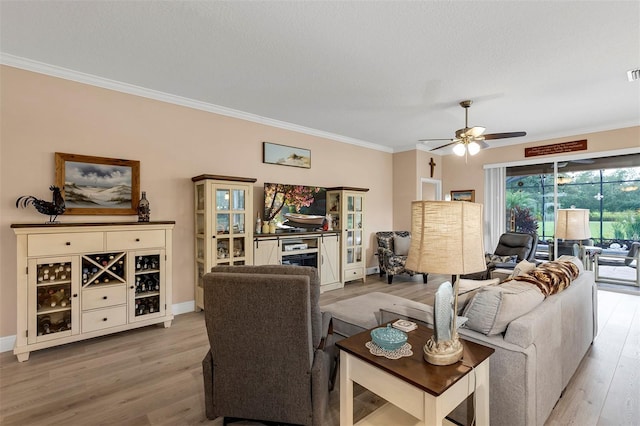 living room featuring ceiling fan, light hardwood / wood-style floors, ornamental molding, and a textured ceiling