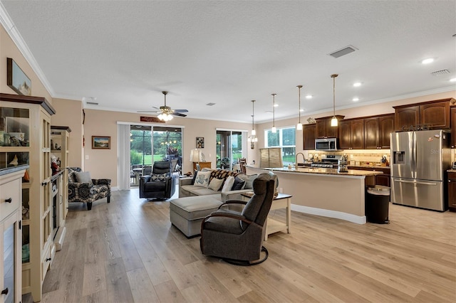 living room with a textured ceiling, ceiling fan, light wood-type flooring, and ornamental molding